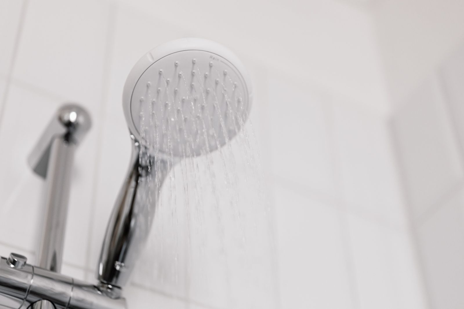 Close view of a white round handheld shower head releasing a gentle rain spray